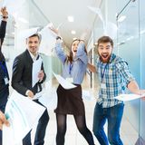 Group of joyful excited business people throwing papers and having fun