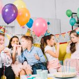 group-children-sitting-sofa-holding-colorful-balloons-blowing-party-ho